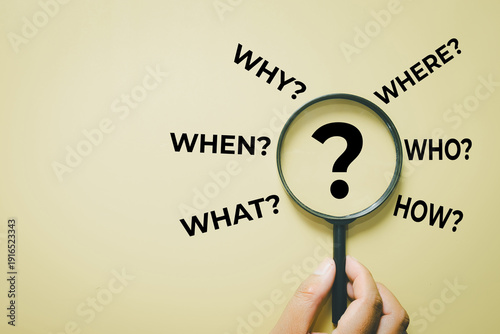 Problem solving and root cause analysis. Hand with lens zooming on question mark with 5W1H words. Concept of strategic planning, research, critical thinking, and finding solution.,copyspace.