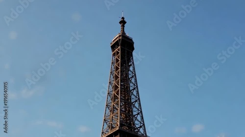 Ascending view of the eiffel tower against a clear blue sky showcasing its iconic silhouette with natural light highlighting its details