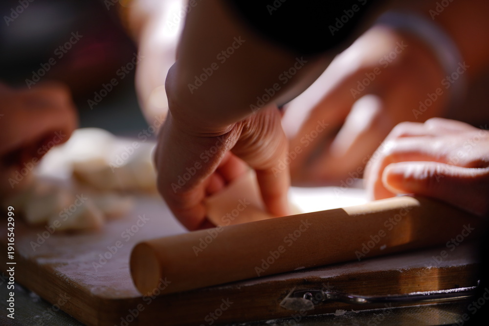 Obraz premium A young home cook meticulously prepares Chinese dumplings on a worn