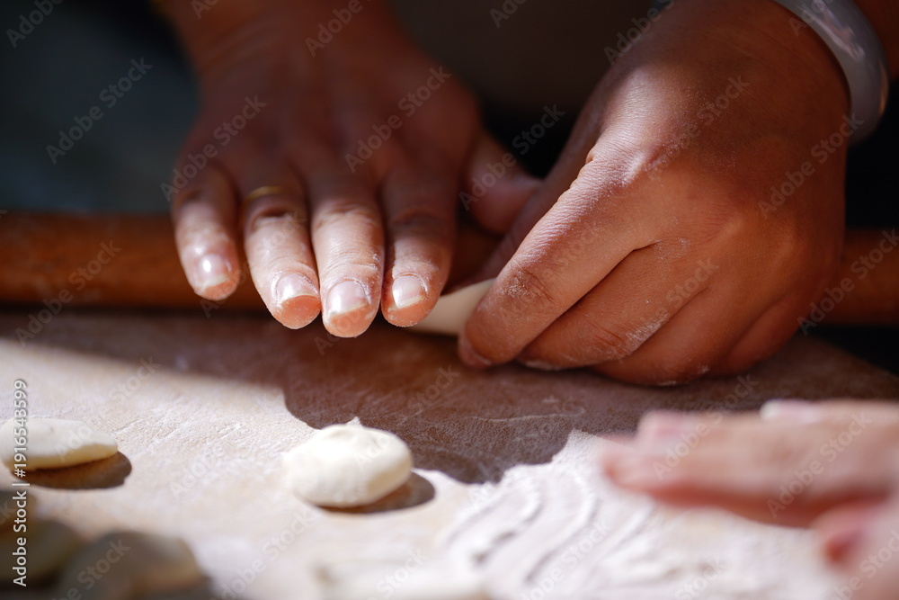 Fototapeta premium A skilled hand meticulously crafts dumplings on a rustic table