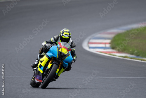 Canvastavla Professional motorcyclist in racing gear leaning deep into a corner on a blue and yellow sport bike on a racetrack