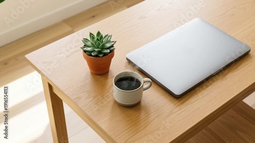 A high-angle shot of a minimalist wooden desk with a single steaming cup of black coffee, a small green succulent, and a closed premium laptop.