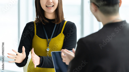 Photos 打ち合わせで会話する女性社員と男性社員, Business colleagues talking during meeting in office