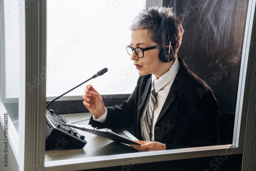 Foto Female interpreter wearing headset speaks into microphone while seated at desk w