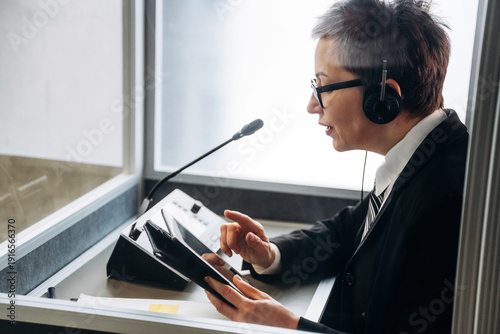 Cuadro en lienzo Female interpreter wearing headset and suit uses tablet while working in soundpr