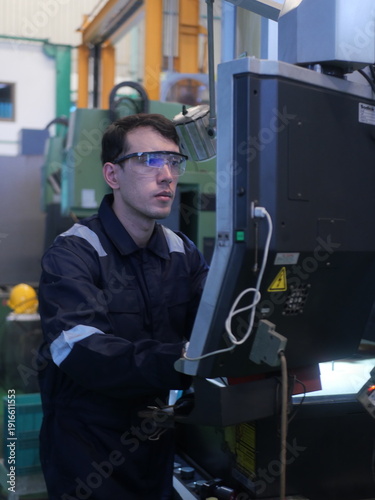 Factory engineer inspecting machining process on CNC machine in automotive manufacturing plant
