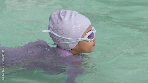slow motion of preschool child girl playing and swimming in the pool