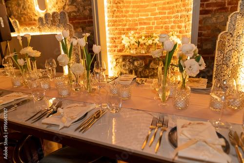 Close up view of wedding table setting with flowers and candles in a warm scene.