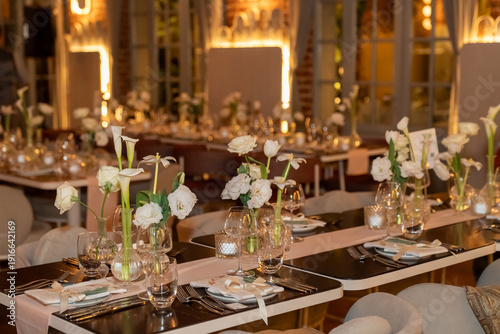 Close up view of wedding table setting with flowers and candles in a warm scene.