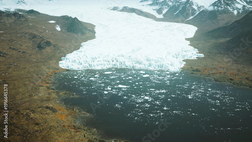 Obraz na płótnie Majestic glacier flows into a calm lake, surrounded by rugged mountains and rocky terrain
