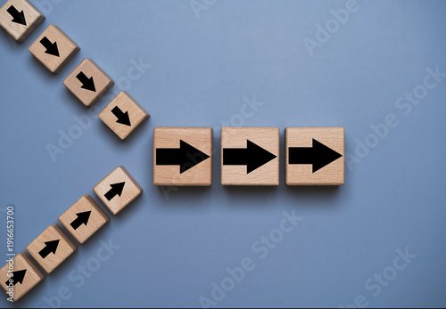 Photos Merge and acquisition business concept with wooden arrow blocks changing direction and aligning into one path