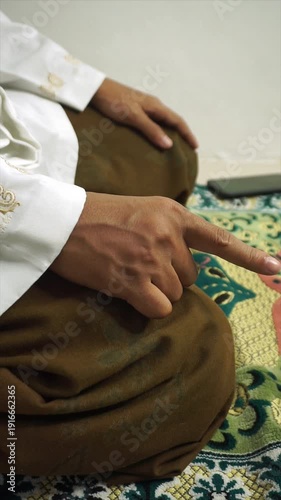 a Muslim is performing the prayer where his index finger moves