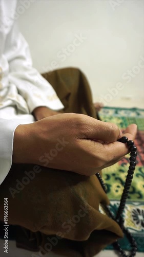 a Muslim is reciting dhikr using prayer beads on a white background