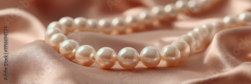 Lustrous pearl necklace draped on soft champagne satin, showcasing elegant, timeless jewelry and luxurious texture.