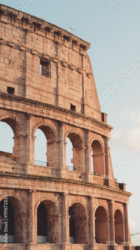 Famous Roman Colosseum, an ancient amphitheater and UNESCO world heritage site, glowing under the warm sunlight of a clear day, a testament to imperial Roman architecture and history in Italy