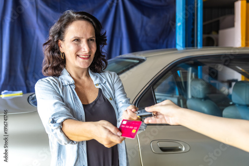 Φωτογραφία Woman customer standing in front of auto repair service shop receive car key, ho