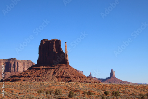 West Mitten illuminated by clear morning light with distant sandstone buttes in Monument Valley, Arizona, USA.