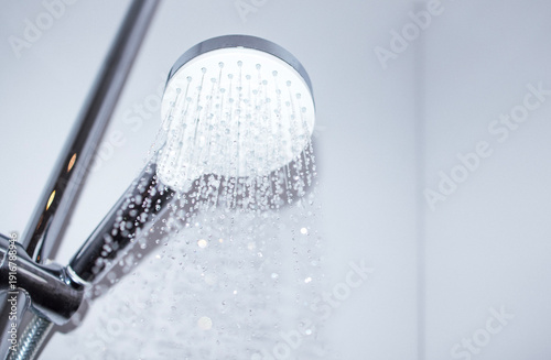 Photos Modern chrome showerhead with water droplets cascading down, mounted on a sleek
