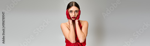фотографія Young woman poses elegantly in a stunning red outfit against a neutral backdrop