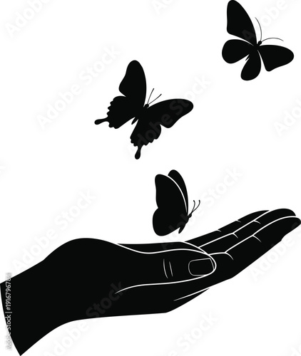 Black silhouette of a human hand held out as butterflies fly around for nature beauty transformation freedom and peaceful mindfulness lifestyle concepts on black.
