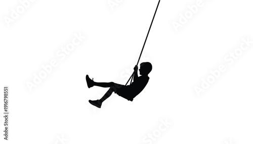 Black silhouette of a child having fun playing on a rope swing.