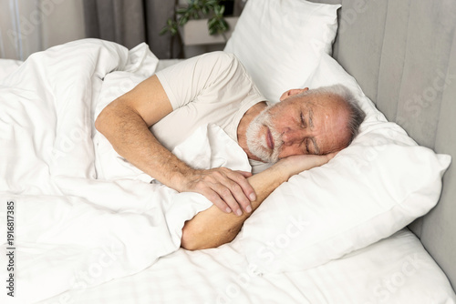 Bilde på lerret Cozy morning in hotel bed with elderly man enjoying peaceful sleep and relaxatio