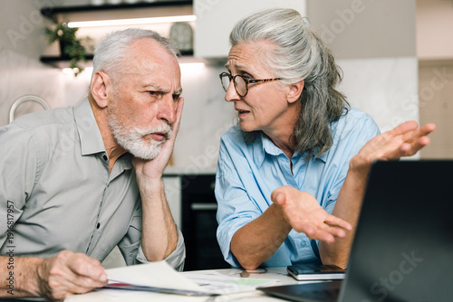 Fotografie Couple discussing household finances while using laptop at home