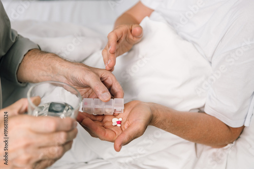 Valokuva Senior man gives wife medicine at home, close up