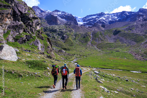 Three male mountaineers and mountain glacier panorama in summer in Pennine Alps, Italy