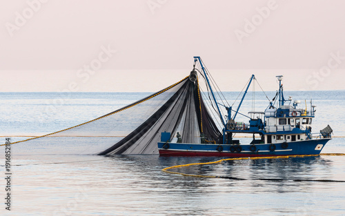 Картината върху платно The fishing boat is casting its nets into the sea hoping for a good catch