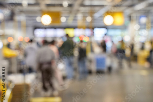 Blurred crowd in busy shopping mall with diverse adults and teens engaged in shopping activities.