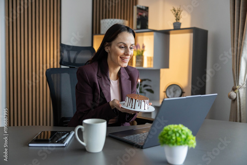 Εκτύπωση καμβά A woman gleefully holds a lit birthday cake during a video call, celebrating a cherished moment