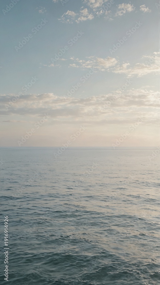 Fototapeta premium Calm sea horizon under soft cloudy sky at sunset