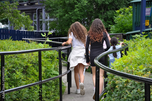 Back view of girls walking on concrete path 
