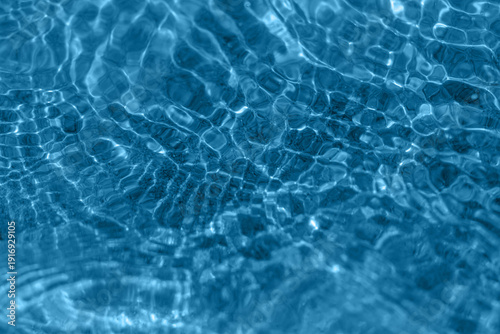Sunlit blue pool water rippling into a mesmerizing abstract pattern, showing ...
