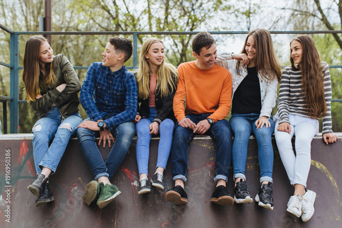 Quadro su tela Group of diverse teenagers sitting together in a skate park, smiling and chattin