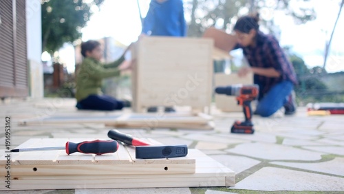 Family enjoying diy project, parents and children building wooden furniture together, fostering teamwork and learning skills for home improvement in backyard