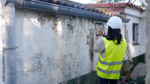 Schilderij op canvas Building inspector examining an old wall for moisture, dampness, and mold damage