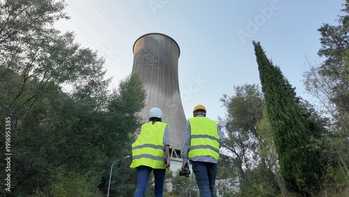 Fotografía Engineers and technicians in hard hats and reflective vests walk toward a large