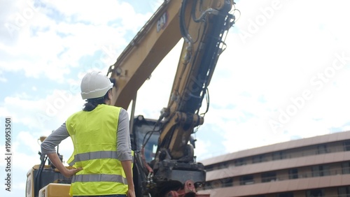 Fotografía Woman construction worker in hard hat and safety vest standing at a building sit