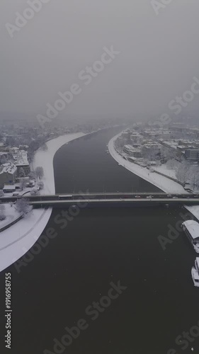 Winter vertical drone shot of snowy Vistula River with Grunwald Bridge in view. 