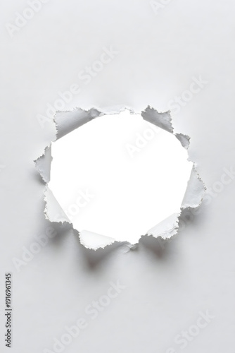 A torn paper edge with a white center on a gray background, viewed from directly above, showcasing a ripped texture and shadow effect
