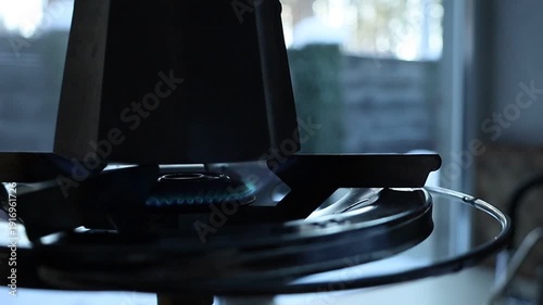 Coffee brewing on a gas stove during a power outage. Close-up of a pot heating over an open flame in a kitchen without electricity, highlighting everyday adaptation and resilience during an energy cri