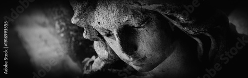 Photos Close view of a sorrowful angel, eroded by time, reflecting grief, compassion, and acceptance of life’s fragile impermanence