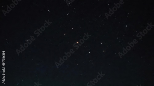 Night sky with stars and constellations over dark horizon.