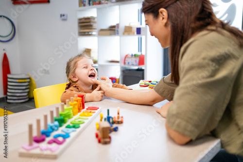 Tableau sur toile Speech therapist guiding a smiling preschool girl through playful articulation e