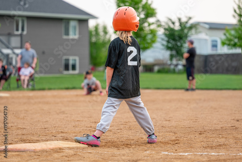 Photography Child playing baseball on a field during a game in a neighborhood park in the ev