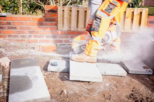 builders cutting, measuring and laying concrete block to build a wall wearing full personal protection equipment 
