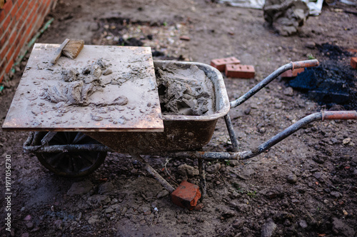 well barrow full of mortar with trowels and tools for building a wall dirty works 