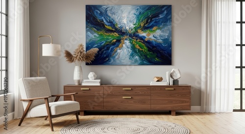 Modern living room interior featuring abstract blue artwork above wooden sideboard and comfortable chair with natural light
